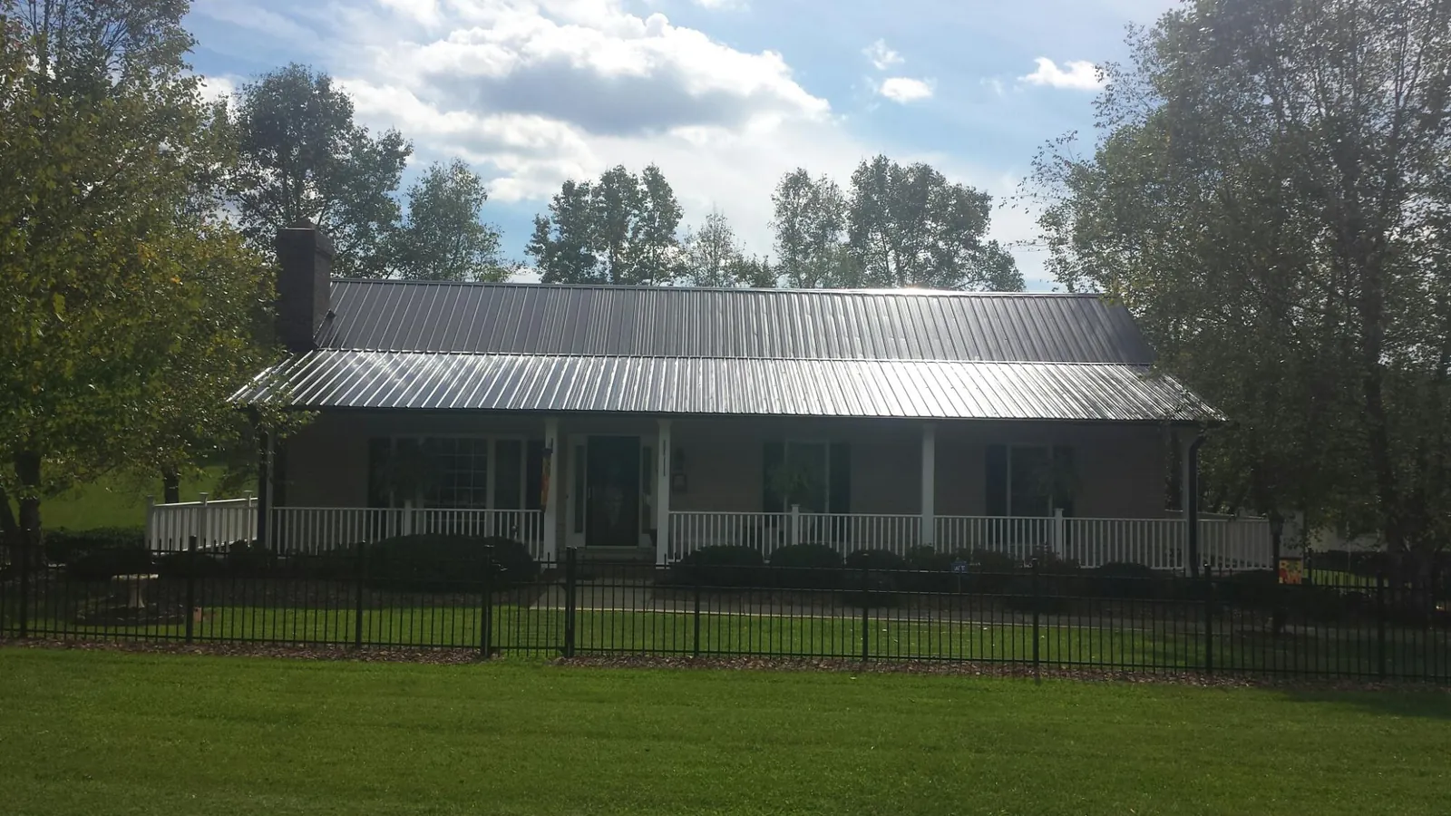 Gray metal roof on a brick ranch with a full width front porch — Gutter Guard Installation work by our crew in Laurel